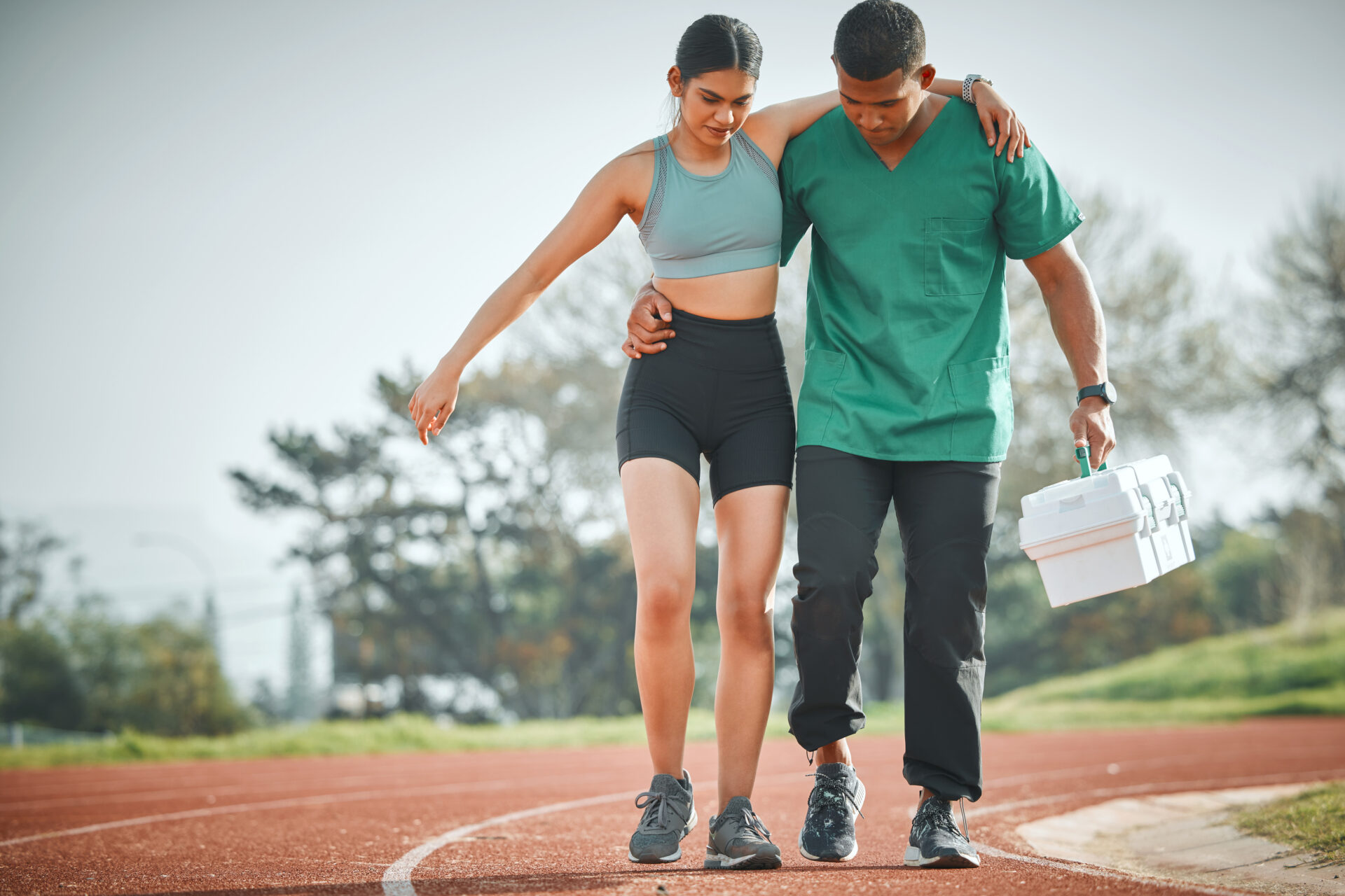 Shot of a sports paramedic providing first aid to an athlete on a running track